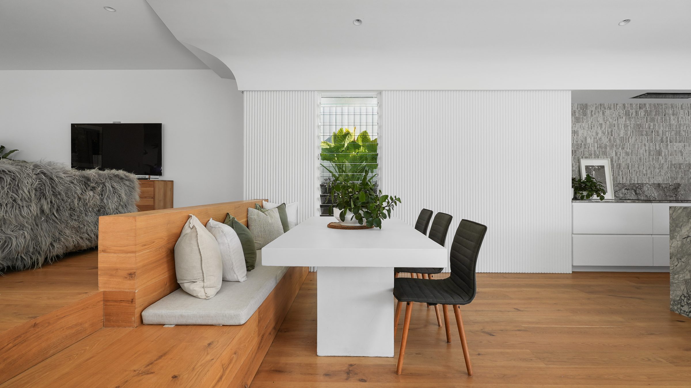 Dining table with built-in bench seat and fluted wall