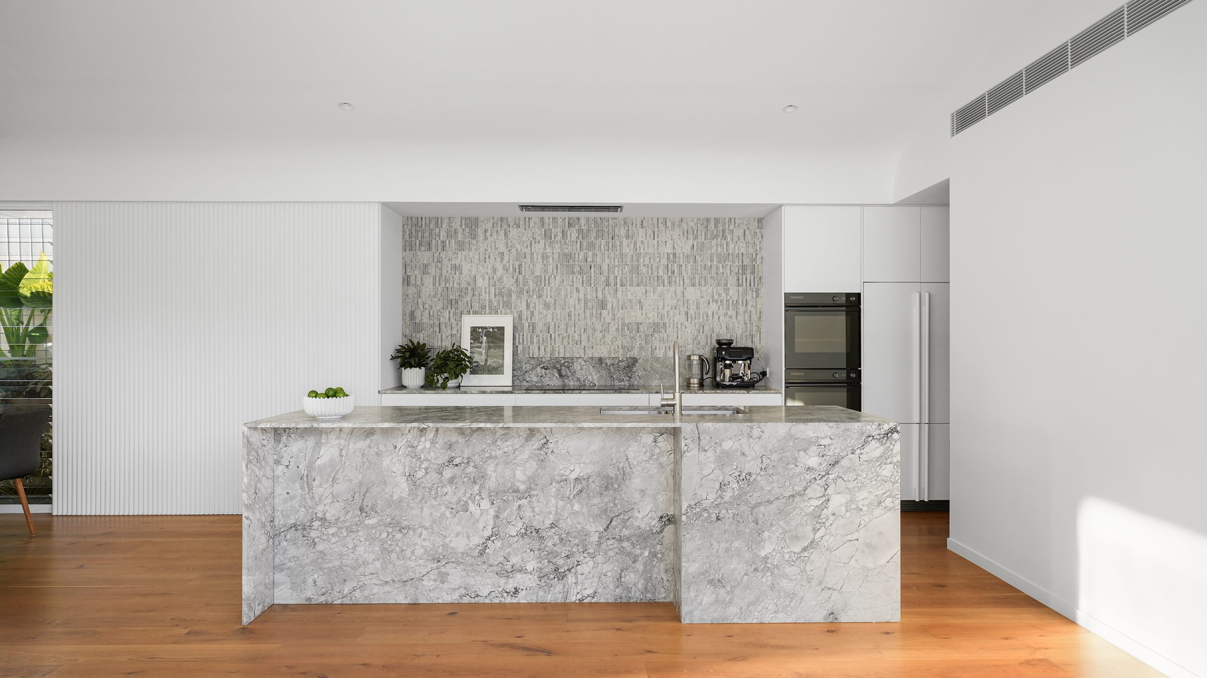 Kitchen with marble island and tiled splashback