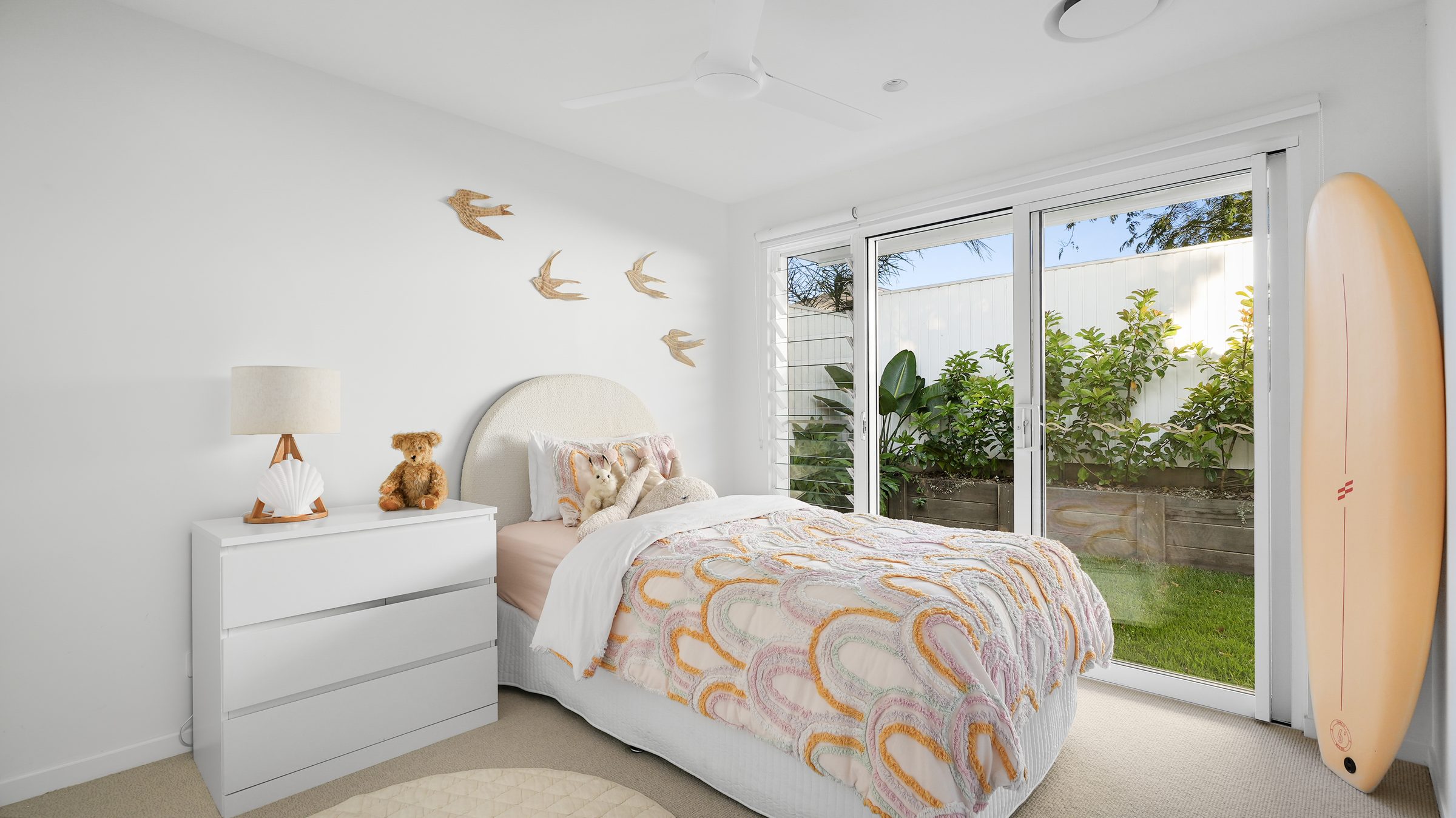 Kid's bedroom with surfboard and pastel quilt